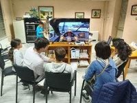 Un grupo de alumnos están sentados jugando alrededor de una pantalla