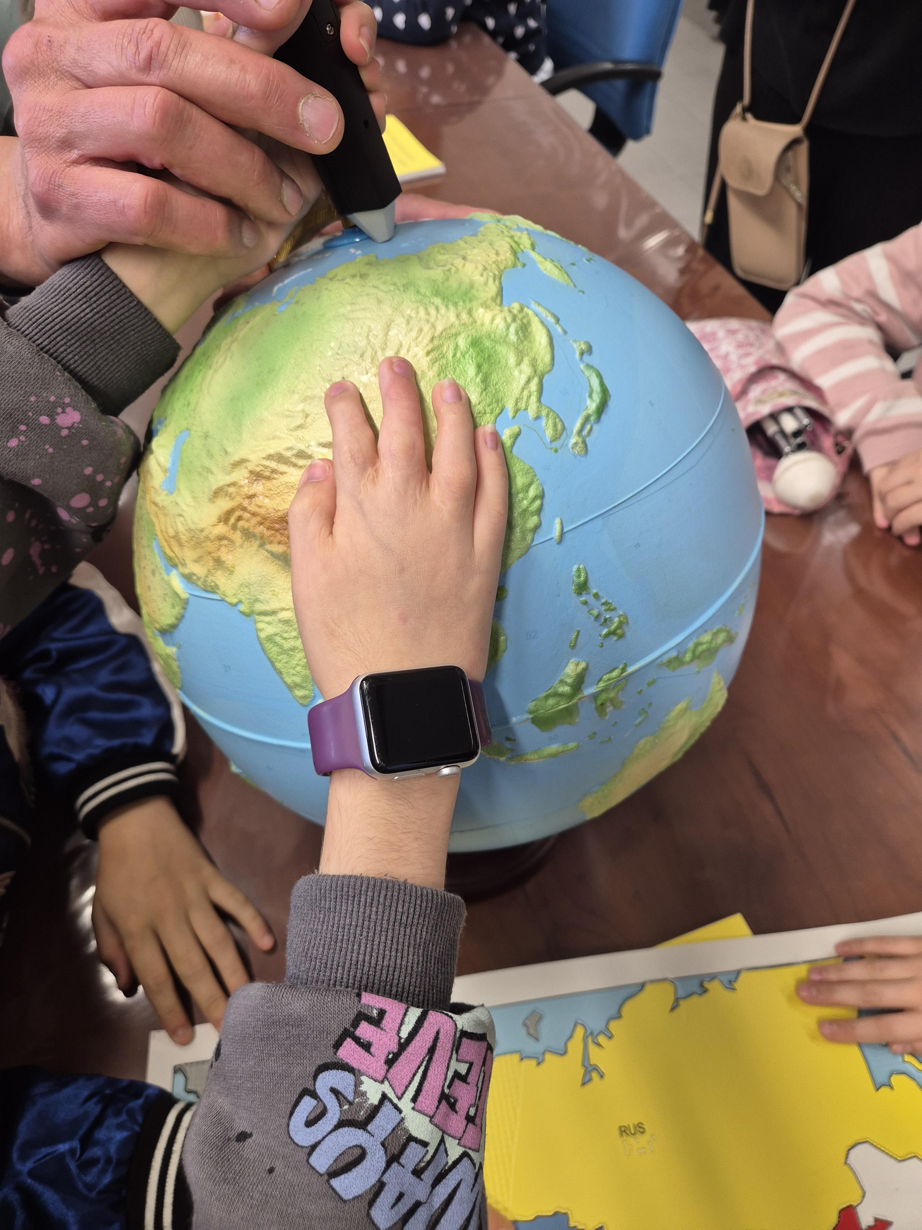 Alumnos tocando bola del mundo interactiva