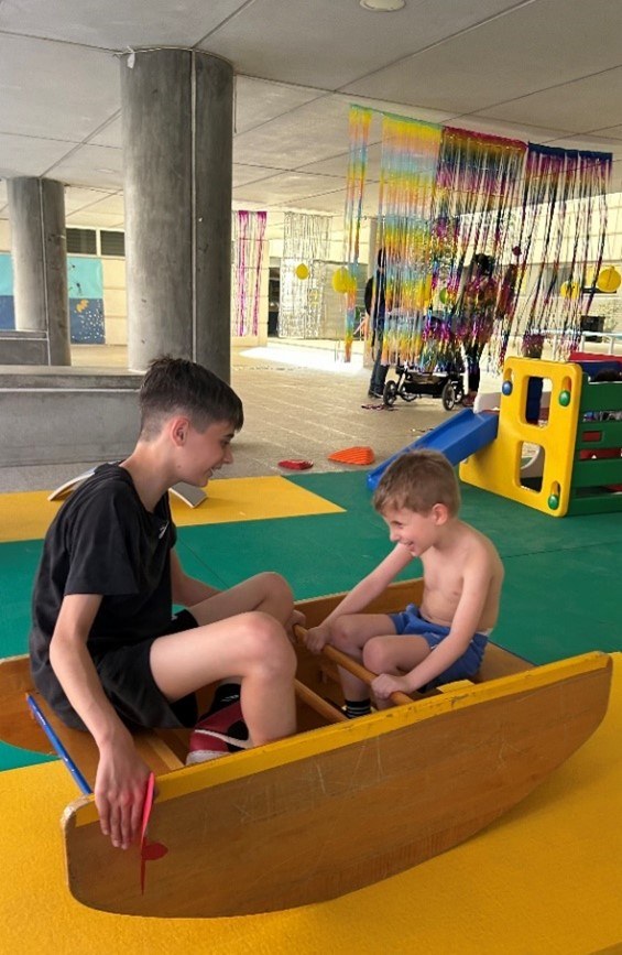 Dos hermanos se encuentran en una barca de madera, que es un balancín