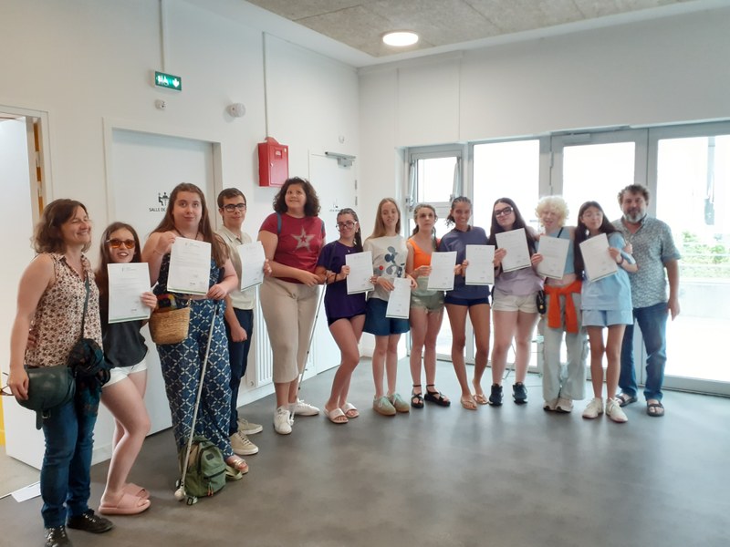 Estudiantes enseñando su diploma con los profesores de francés