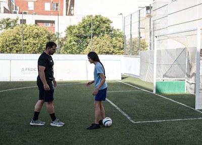 Alumna jugando a fútbol con un entrenador Alumna jugando a fútbol con un entrenador