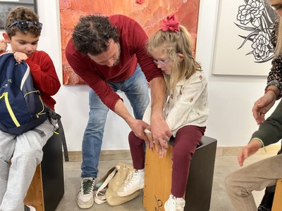 Monitor de percusión enseñando a una alumna a colocar las manos en el cajón flamenco. Monitor de percusión enseñando a una alumna a colocar las manos en el cajón flamenco.