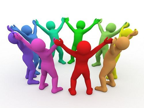La imagen muestra un grupo de figuras humanas simplificadas, sin rasgos faciales, de diferentes colores formando un círculo. Todas tienen los brazos levantados y parecen unidas, lo que sugiere colaboración, celebración o trabajo en equipo. El fondo es blanco y simple, sin elementos adicionales.