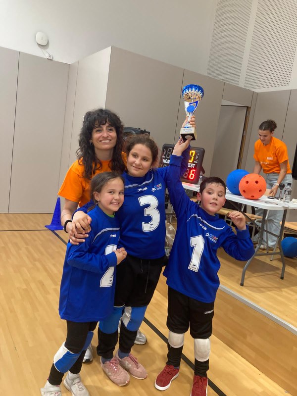 Dos niñas y un niño con la copa ganadora