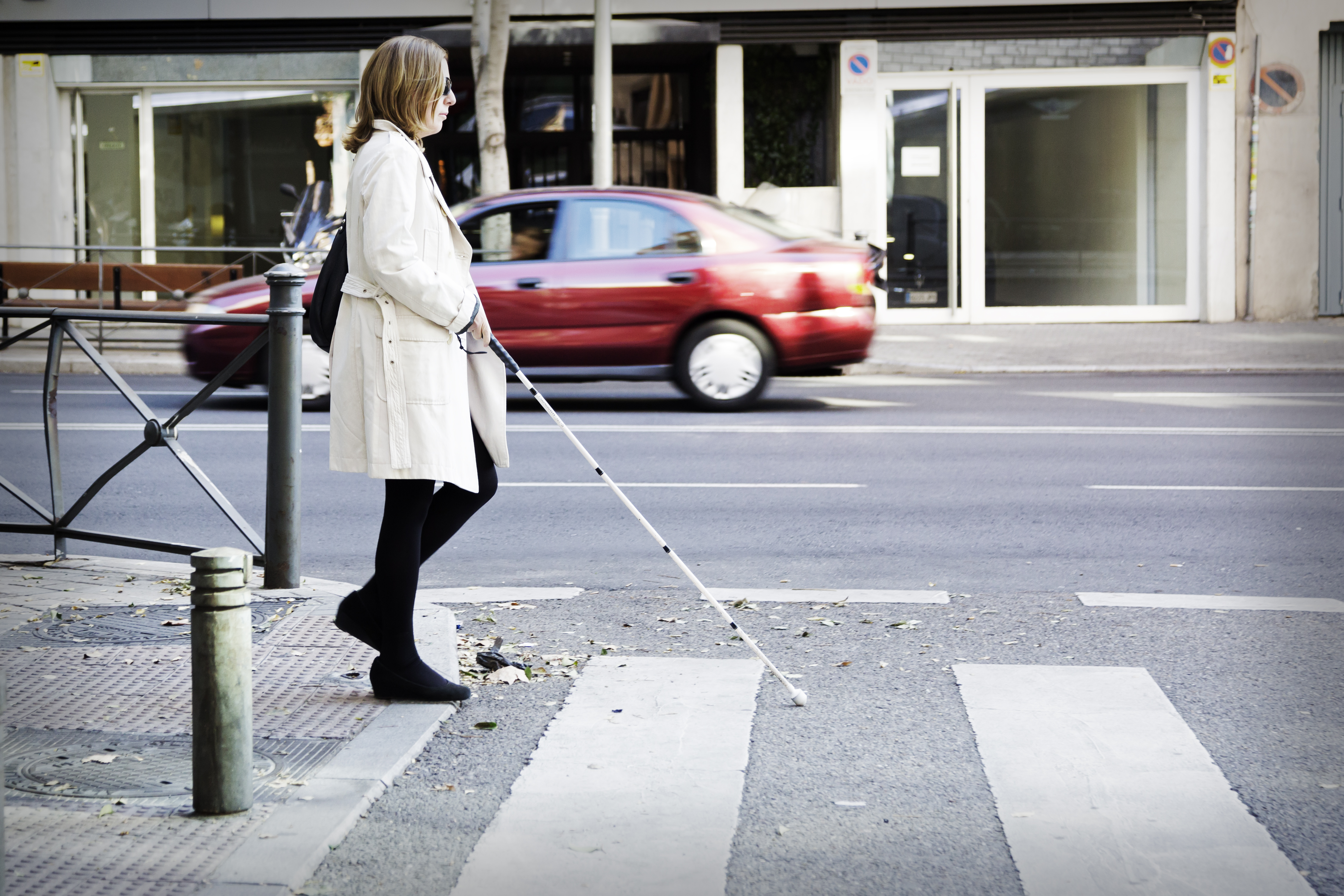 Mujer con bastón cruzando paso de cebra. 