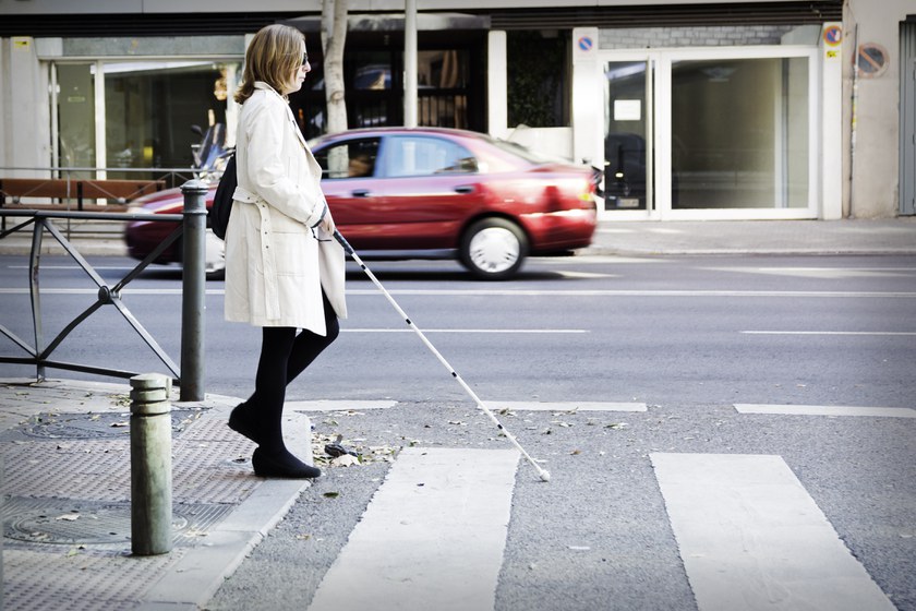 Mujer con bastón cruzando paso de cebra. 