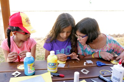 Tres niñas realizando manualidades en una mesa repleta de material de papelería