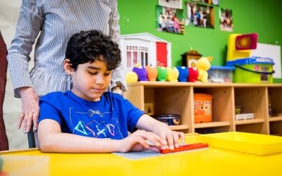 Alumno en el aula manipulando un material junto a su maestra