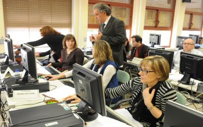 Grupo de personas adultas en un aula de informática escuchando al formador